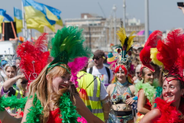 A troupe of dancers in bright colourfull dresses laugh in the sun